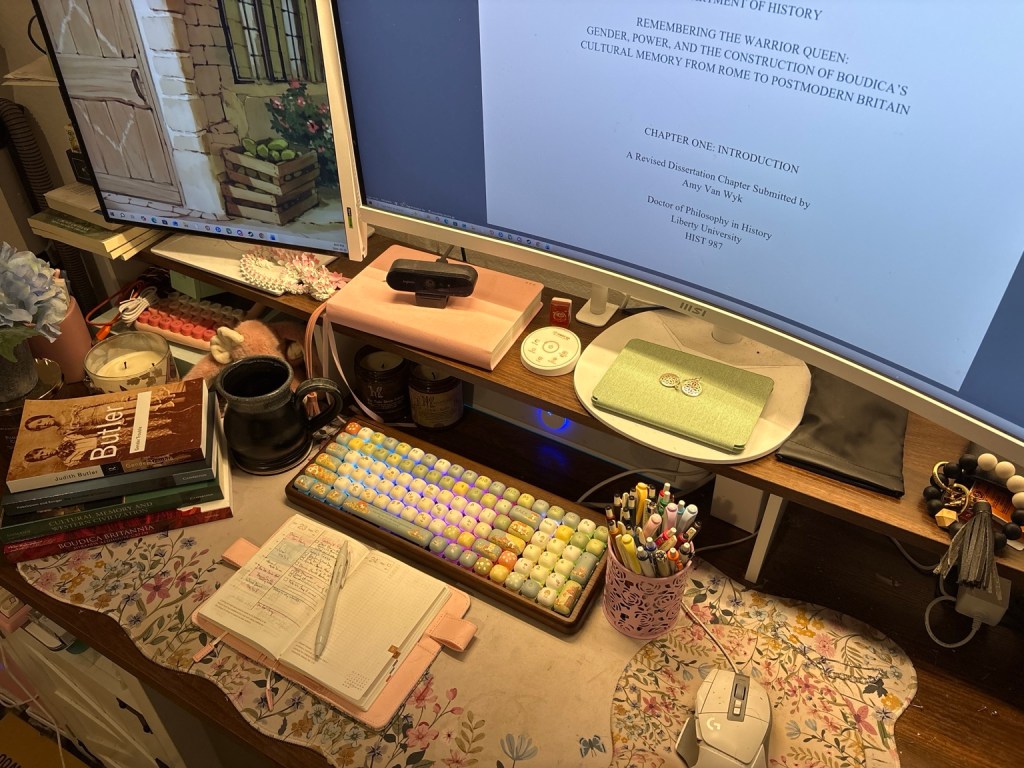 Dissertation workspace with Boudica research books, an open planner, and a computer displaying a History Ph.D. dissertation chapter.